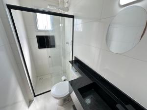 a white bathroom with a toilet and a mirror at Apto vista Mar c/ vaga a 200m da Praia da Mirim! in Praia Grande +50 photos
