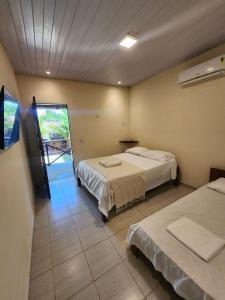 a hotel room with two beds and a window at Pipa Villa Mar in Pipa