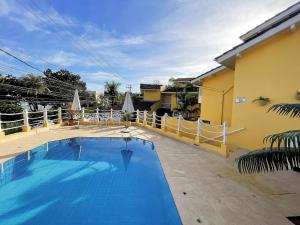 a large blue swimming pool next to a yellow building at Home 80 I Casa em condomínio pé na areia em Juquehy WIFI e Piscina in São Sebastião