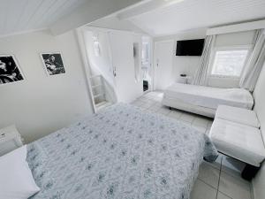 a white bedroom with two beds and a television at Home 80 I Casa em condomínio pé na areia em Juquehy WIFI e Piscina in São Sebastião +40 photos