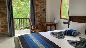 a bedroom with a bed and a balcony with a table at AHU hiriketiya in Hiriketiya