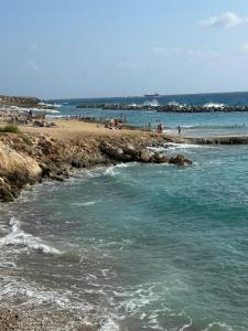 a beach with people on the sand and the water at Pelagos Hill Apartment in Paphos