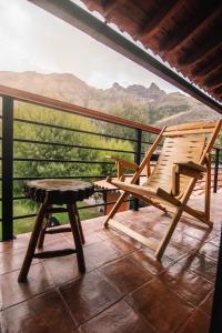 Una mecedora y un banco en un balcón con montañas. en Family Friendly home in the Sacred Valley, en Calca