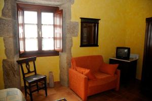 a living room with an orange chair and a television at Casa Casarellos in Casarellos