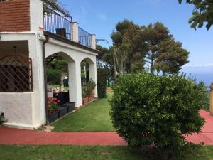 a house with a porch and a yard with a bush at Villa Eleanto in Cefalù