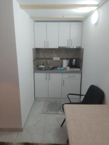 une cuisine vide avec des placards blancs et une table dans l'établissement Apartman Dragana, à Sremska Mitrovica
