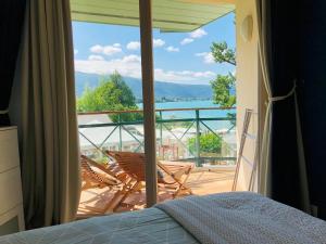 een slaapkamer met uitzicht op een balkon met stoelen bij Superbe Duplex Vue Lac et Château avec Plage et parking Privés in Duingt +43 foto's