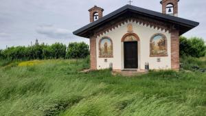 チェルトーザ・ディ・パヴィーアにあるFARM-AgriHotelの草原にある古い教会