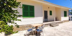 a table and chairs in front of a house with green shutters at Regina house in Metaxáta