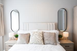 a bedroom with a white bed with two mirrors at Birmingham Central Cosy 4BR Home with Free Parking in Birmingham