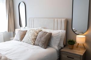 a bedroom with a white bed with pillows and a mirror at Birmingham Central Cosy 4BR Home with Free Parking in Birmingham +59 photos