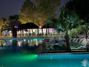 a swimming pool at night with chairs and trees at Little Ranch Hotel Spa Pilar in Manuel Alberti