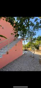 a red building with stairs next to a tree at Fiskouri Anthem in Preveza