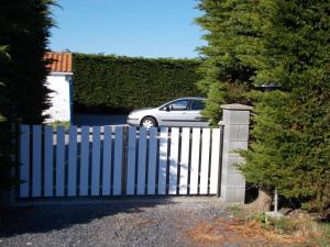 une clôture blanche avec une voiture dans une allée dans l'établissement Le journal Blanc, à Notre-Dame-de-Monts