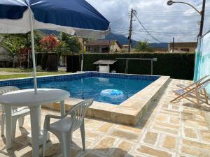 a table with an umbrella next to a swimming pool at Pousada Recanto dos Leporage Itacuruçá in Mangaratiba