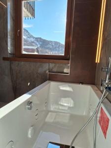 eine weiße Badewanne in einem Badezimmer mit Fenster in der Unterkunft Cervinia Exclusive in Breuil-Cervinia
