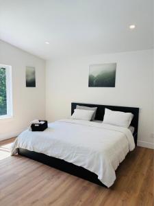 a bedroom with a large bed with white sheets at Castle BNB 2025 in Gibsons