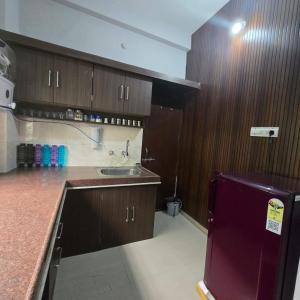 a kitchen with wooden cabinets and a sink and a refrigerator at Satyabhama Homestay-Sapphire- two bhk Luxury appartment in Indore