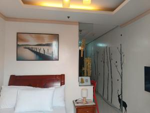 a bedroom with a bed and a painting on the wall at BirchTower Studio Condo with Balcony & Pool - Carosa Staycation in Manila +83 photos