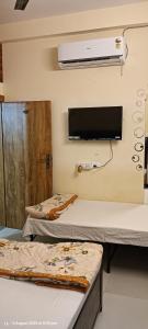 a hospital room with two beds and a tv on the wall at Parvati home stay in Ujjain