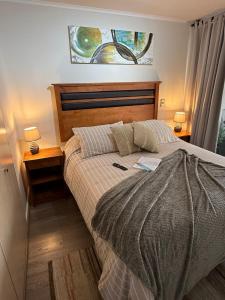 a bed in a bedroom with two night stands and two lamps at Moderno Dpto Vista al Mar y Piscina Temperada in La Serena