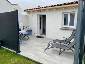 eine Terrasse mit 2 Stühlen und einem Tisch vor einem Haus in der Unterkunft Maisonnette cosy au calme terrasse local vélo in Rochefort + 4 Fotos