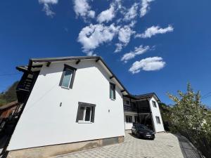a white house with a black roof at Casa IL LUCE in Câmpulung Moldovenesc