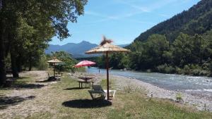 a picnic table and an umbrella next to a river at Les Acacias in Vercheny