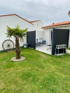a palm tree in a yard next to a house at Maisonnette cosy au calme terrasse local vélo in Rochefort