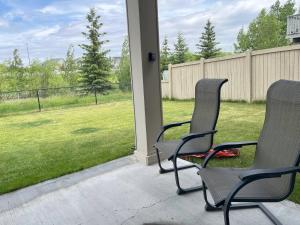 - deux chaises sur une terrasse couverte donnant sur une cour dans l'établissement Tranquille pond facing suite, à Nisku