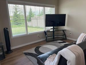 un salon avec un canapé et une télévision à écran plat dans l'établissement Tranquille pond facing suite, à Nisku