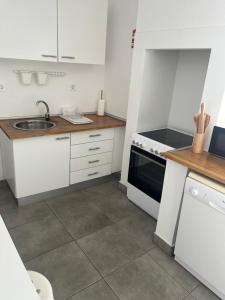 a small kitchen with white cabinets and a sink at Duplex no estoril in Estoril