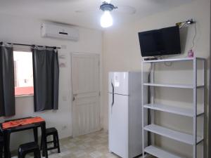 a kitchen with a refrigerator and a tv on a shelf at Chalés Bielle de Ubatuba in Ubatuba