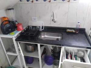 a kitchen counter with a sink and a shelf at Chalés Bielle de Ubatuba in Ubatuba