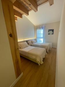two beds in a room with wooden floors and a window at Hotel Apartamento Los Villares in Los Villares de Soria