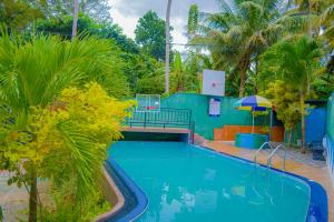 a swimming pool with a blue house and palm trees at Villa Acadia Bentota in Bentota