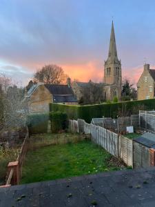 a church with a steeple and a yard with a fence at The Dunkirk Avenue Nest in Desborough