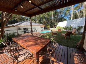un tavolo e sedie in legno su una terrazza con piscina di Casa 23 Floresta Boa Vista - 4 Suítes e Piscina Aquecida em Meio à Natureza a Teresópolis