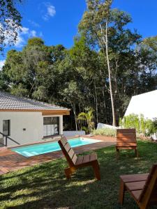 un cortile con piscina e due sedie di Casa 23 Floresta Boa Vista - 4 Suítes e Piscina Aquecida em Meio à Natureza a Teresópolis Altre 43 foto