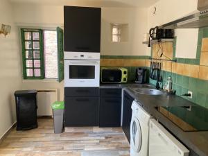 a small kitchen with a sink and a microwave at Les Remparts de Sainte-Suzanne in Sainte-Suzanne