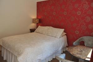 a bedroom with a bed and a red wall at Mays Cottage Bed and Breakfast in Petersfield