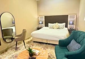 a bedroom with a bed and a mirror and a chair at البندقية للخدمات الفندقية BQ HOTEL SUITES in Buraydah +69 photos