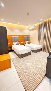 a hotel room with two beds and a carpet at شقق تالا للوحدات السكنية Furnished Units Tala in AlUla