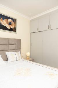 a white bedroom with a large bed and white cabinets at Peaceful Nest Apartment in Kigali +28 photos