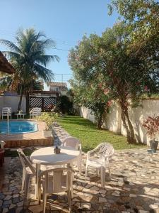 a patio with a table and chairs next to a pool at Casa de temporada piscina com proxima a praia in Saquarema