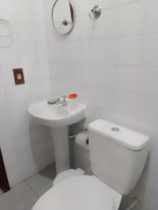 a white bathroom with a toilet and a sink at Casa de temporada piscina com proxima a praia in Saquarema