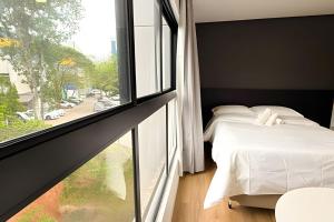 a bedroom with a bed and a large window at ASA | Loft UP ao Lado da FURB | Piscina + Oktober in Blumenau +13 photos