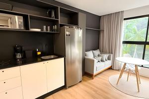 a kitchen with a refrigerator and a table and a chair at ASA | Loft UP ao Lado da FURB | Piscina + Oktober in Blumenau