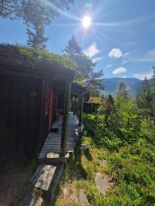 a wooden porch of a cabin with the sun in the sky at Hov Hyttegrend in Viksdalen