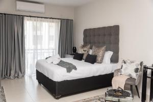 a bedroom with a large bed and a chair at MM Stays G206 at Habitat Kappa - Sarona City in Gaborone +22 photos